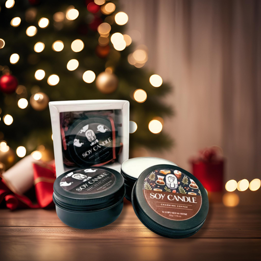 Two soy wax candles, one labeled 'COFFEE' and the other 'STRAWBERRY', are displayed in front of a Christmas tree. The candles are in black containers with white lids, one lid is off showing the product label.